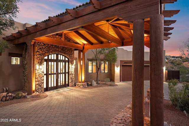 view of patio / terrace with a garage, decorative driveway, and french doors