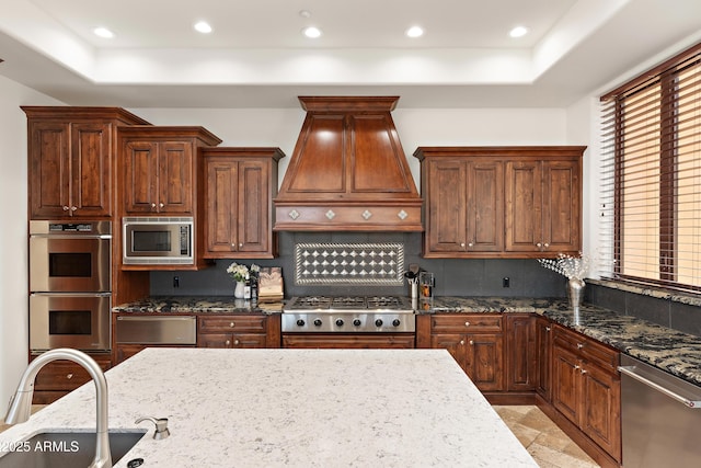 kitchen with appliances with stainless steel finishes, a warming drawer, premium range hood, a sink, and recessed lighting