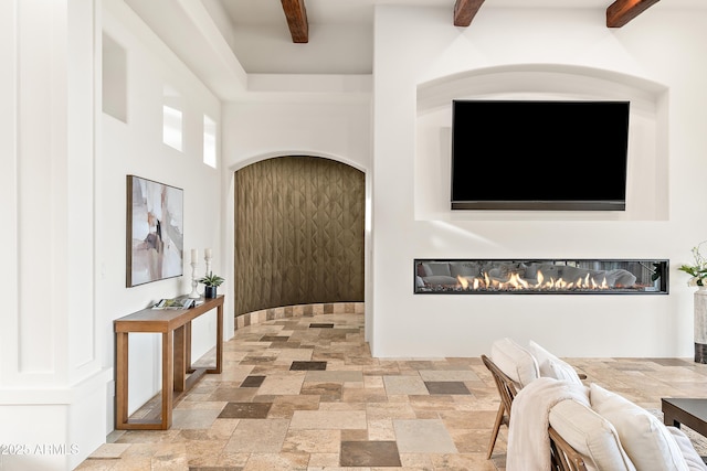 hallway with a towering ceiling, beam ceiling, and stone tile floors