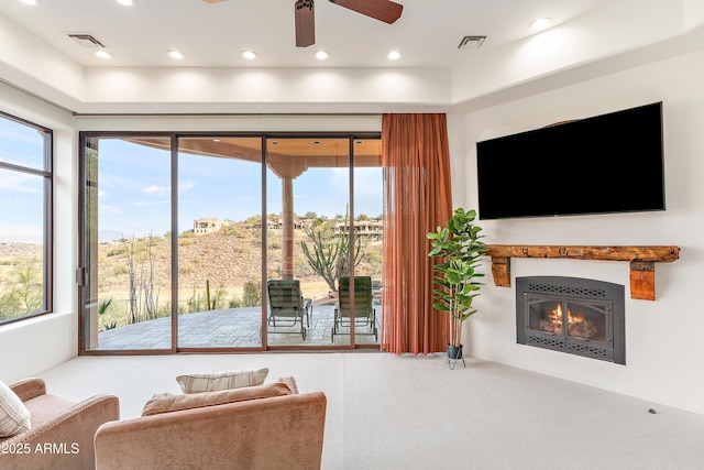 living room featuring carpet floors, recessed lighting, visible vents, and a glass covered fireplace