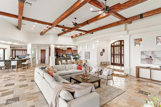 living room featuring decorative columns, stone tile floors, recessed lighting, visible vents, and beamed ceiling