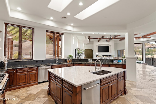 kitchen featuring visible vents, dishwasher, a tray ceiling, stone tile flooring, and a sink