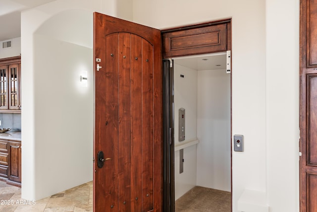 interior space featuring elevator, stone finish flooring, and visible vents