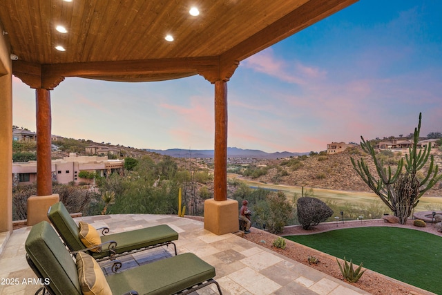 patio terrace at dusk with a mountain view and a lawn