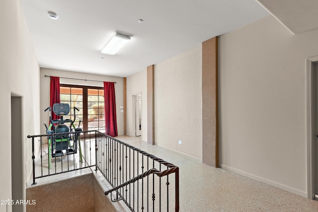 hall with baseboards, speckled floor, and french doors