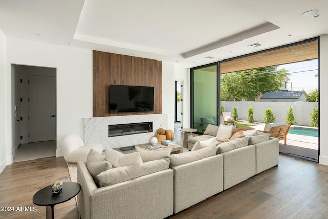 living room featuring hardwood / wood-style floors, a high end fireplace, and a tray ceiling