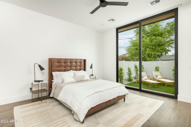 bedroom featuring expansive windows, ceiling fan, hardwood / wood-style flooring, and access to outside