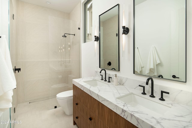 bathroom featuring a tile shower, dual vanity, and toilet