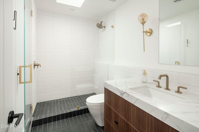 bathroom with tile floors, a tile shower, toilet, tile walls, and oversized vanity