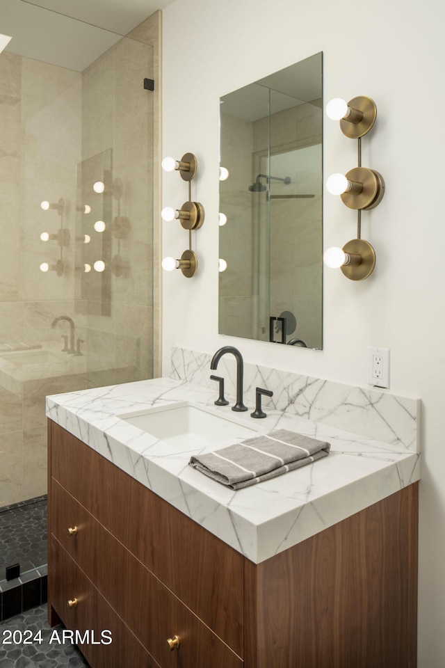 bathroom with tiled shower, vanity, and tile flooring