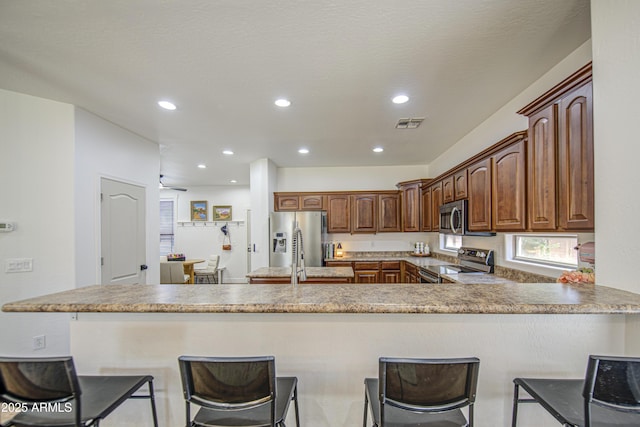 4609 E Ironhorse Rd, Gilbert, AZ 85297 - kitchen with appliances with stainless steel finishes, a peninsula, a breakfast bar area, and recessed lighting