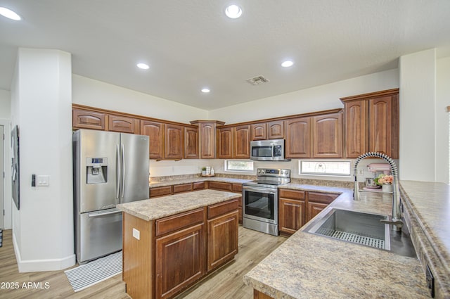 4609 E Ironhorse Rd, Gilbert, AZ 85297 - kitchen with stainless steel appliances, a sink, light wood-style floors, a kitchen island, and light countertops