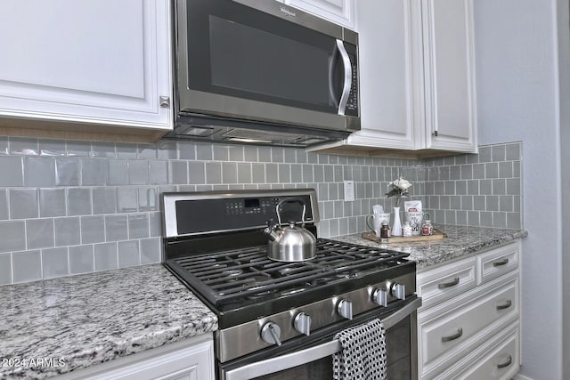 kitchen with decorative backsplash, white cabinetry, and stainless steel appliances