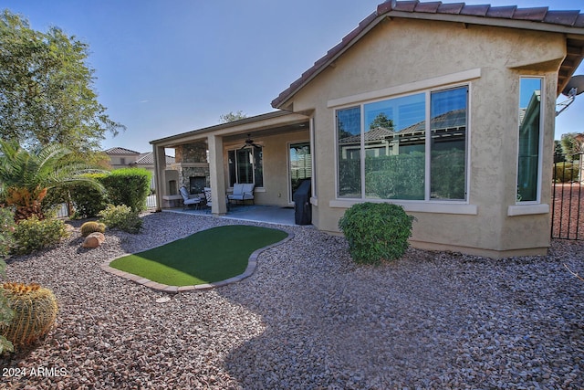 rear view of property featuring ceiling fan, a patio area, and a fireplace