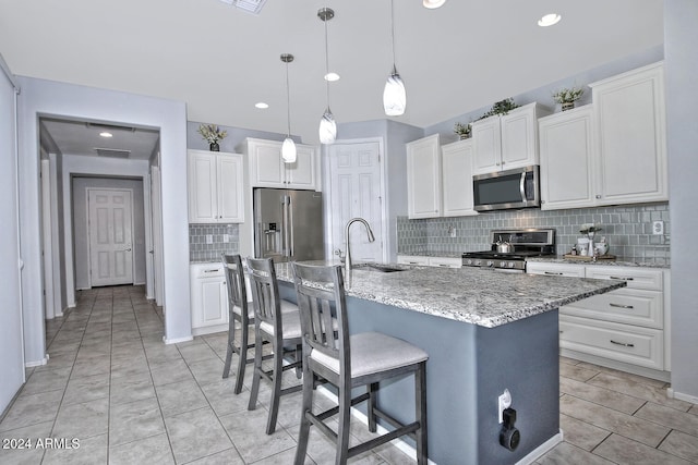 kitchen with a center island with sink, white cabinets, and appliances with stainless steel finishes