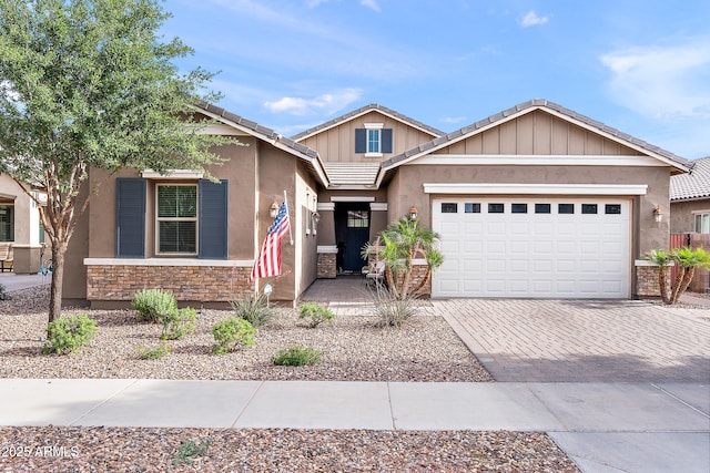 craftsman inspired home featuring a tile roof, stone siding, a garage, stucco siding, and decorative driveway
