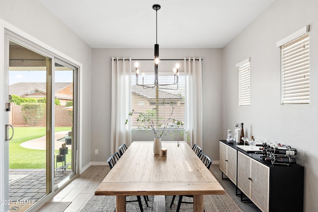 dining area featuring baseboards, a chandelier, and wood finished floors