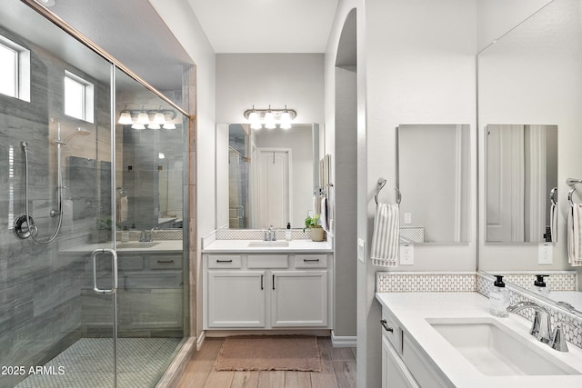 full bathroom featuring a sink, a shower stall, and two vanities