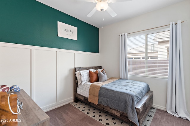 carpeted bedroom with a ceiling fan and a decorative wall