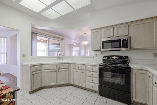 kitchen with tile counters, black electric range, sink, and light brown cabinets