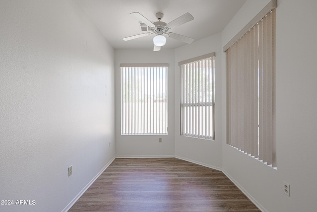 spare room featuring ceiling fan, wood-type flooring, and a healthy amount of sunlight