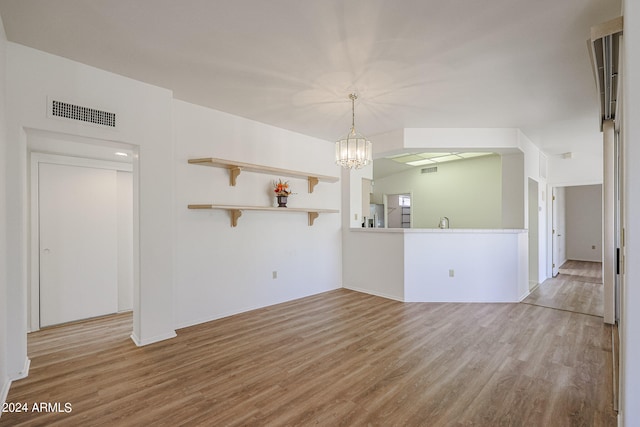 empty room featuring a notable chandelier and light hardwood / wood-style flooring