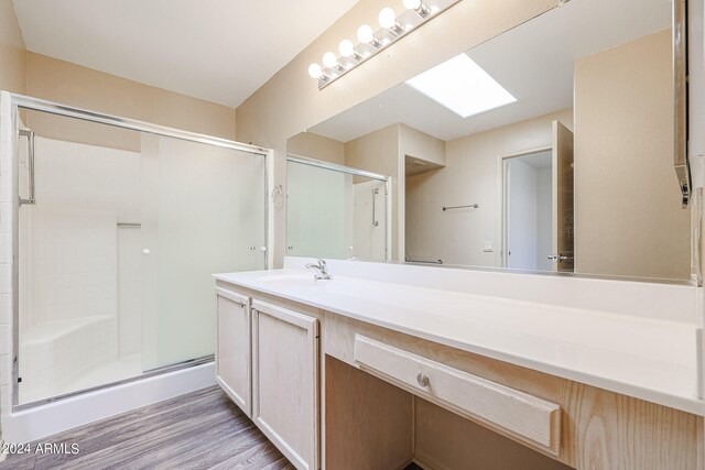 bathroom featuring hardwood / wood-style flooring, vanity, a skylight, and an enclosed shower