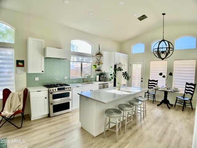 4925 W Bluefield Ave, Glendale, AZ 85308 - kitchen featuring appliances with stainless steel finishes, a breakfast bar, light wood-style flooring, light countertops, and white cabinetry