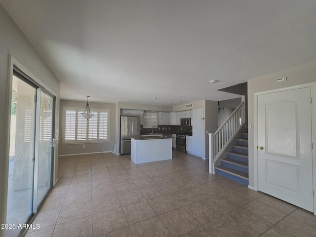 kitchen featuring visible vents, a sink, baseboards, light tile patterned floors, and stainless steel appliances
