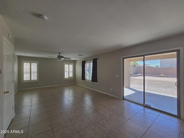 unfurnished room featuring baseboards, tile patterned flooring, a ceiling fan, and a textured ceiling