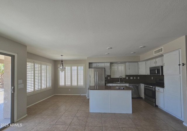 kitchen featuring a kitchen island, visible vents, dark countertops, appliances with stainless steel finishes, and baseboards
