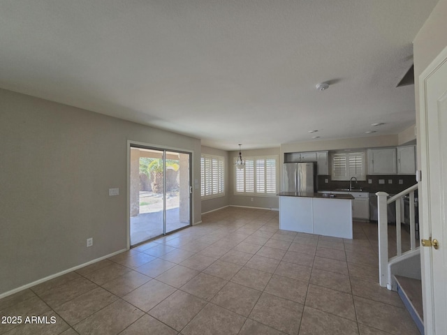 kitchen with an inviting chandelier, tile patterned flooring, freestanding refrigerator, and backsplash