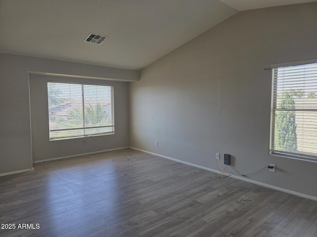 spare room with baseboards, visible vents, dark wood finished floors, and lofted ceiling