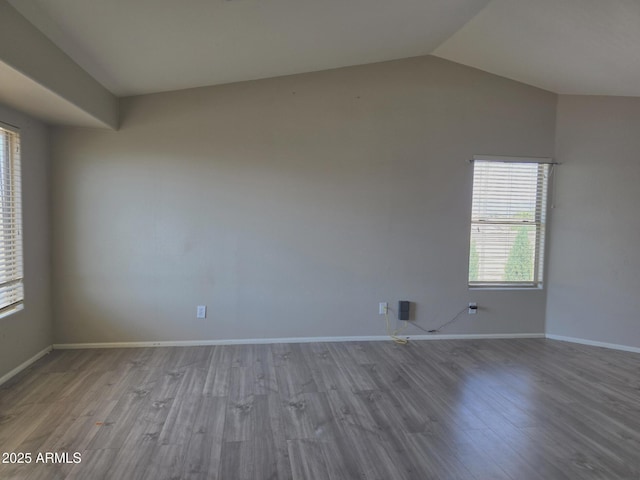 unfurnished room featuring baseboards, wood finished floors, and lofted ceiling
