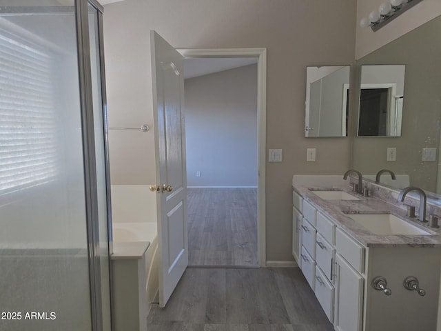 bathroom with a sink, baseboards, a garden tub, and wood finished floors