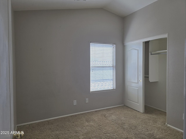 unfurnished bedroom featuring carpet floors, baseboards, vaulted ceiling, and a closet