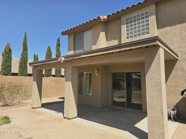 rear view of property with a patio, fence, a tile roof, and stucco siding