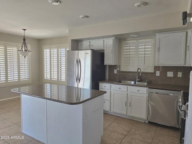kitchen featuring white cabinets, a sink, stainless steel appliances, decorative backsplash, and light tile patterned floors