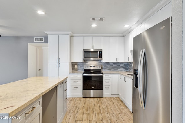 2706 W Isabella Ave, Mesa, AZ 85202 - kitchen with appliances with stainless steel finishes, light wood finished floors, decorative backsplash, white cabinetry, and light stone counters