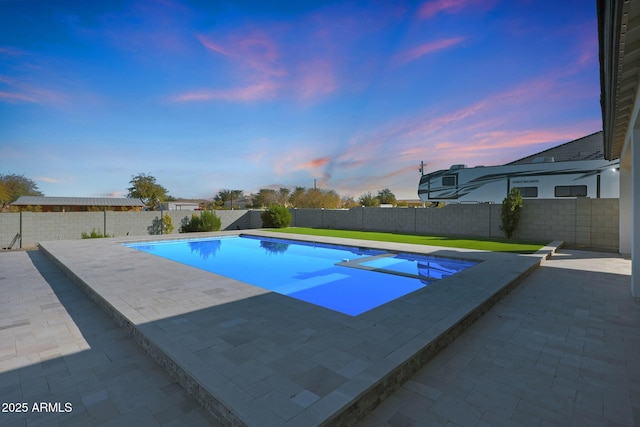 pool at dusk featuring a fenced in pool, a patio area, and a fenced backyard