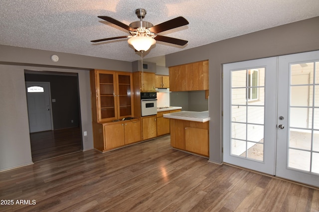 5720 E University Dr, Mesa, AZ 85205 - kitchen with oven, brown cabinetry, light countertops, a textured ceiling, and dark wood finished floors