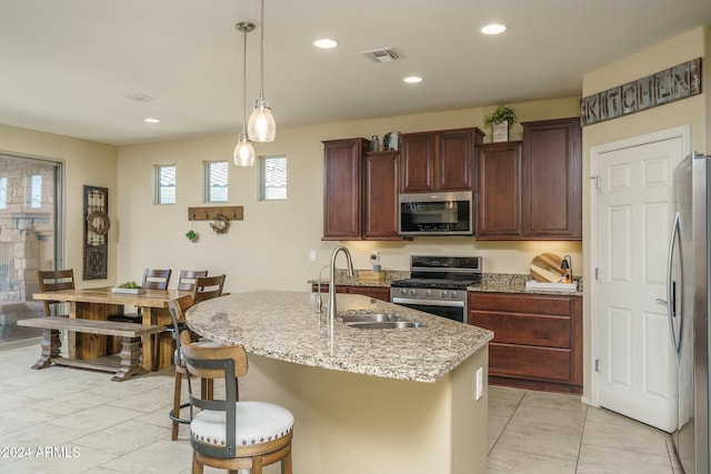 26404 W Zachary Dr, Buckeye, AZ 85396 - kitchen with stainless steel appliances, visible vents, a sink, light stone countertops, and a center island with sink