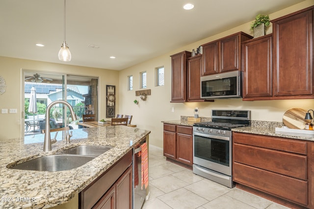 kitchen with light stone countertops, sink, appliances with stainless steel finishes, and hanging light fixtures