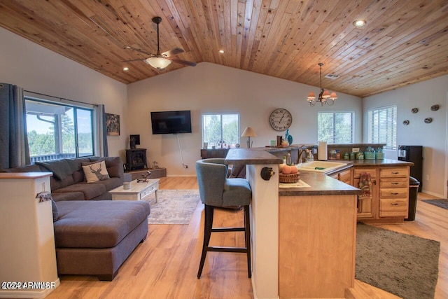 kitchen with decorative light fixtures, light hardwood / wood-style floors, an island with sink, a breakfast bar area, and wooden ceiling