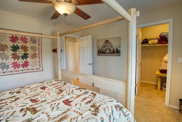 bedroom featuring ceiling fan, a closet, light colored carpet, and a walk in closet