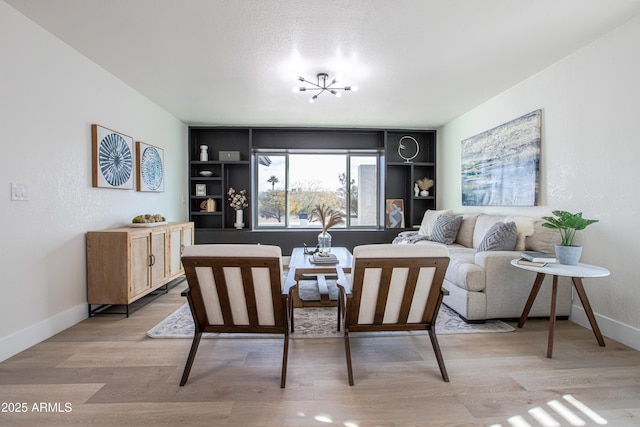 living room featuring light hardwood / wood-style flooring, built in features, and a chandelier