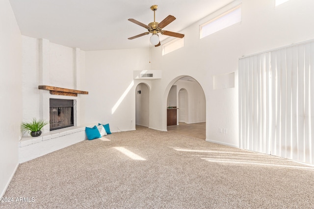 unfurnished living room featuring a large fireplace, light colored carpet, high vaulted ceiling, and ceiling fan