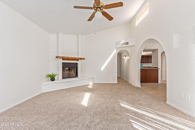 unfurnished living room featuring carpet floors, a large fireplace, and ceiling fan