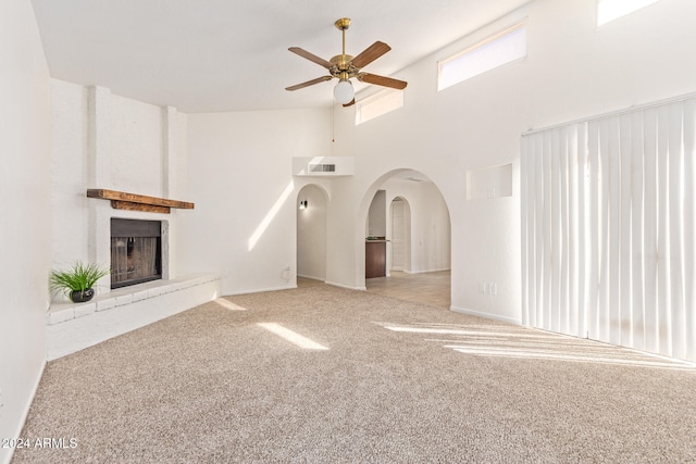 unfurnished living room with light carpet, high vaulted ceiling, a fireplace, and ceiling fan