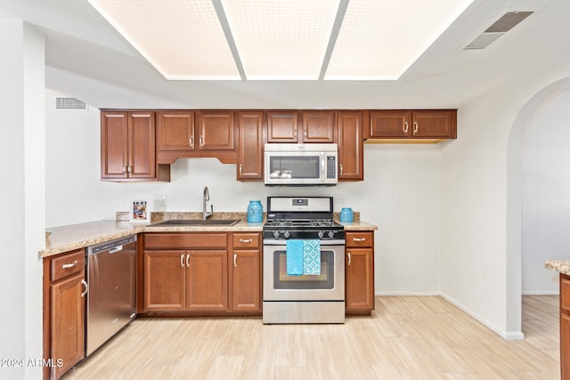 kitchen featuring sink, light hardwood / wood-style flooring, light stone counters, and stainless steel appliances